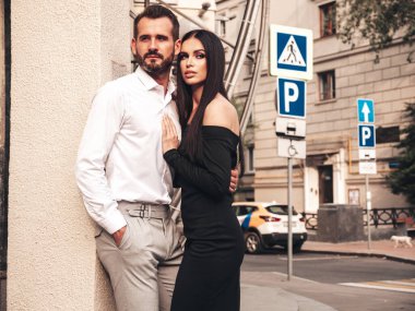 Güzel moda kadını ve takım elbiseli yakışıklı erkek arkadaşı. Siyah gece elbisesi içinde seksi esmer manken. Avrupa 'da sokakta poz veren şık bir çift. Vahşi adam ve dişisi açık havada