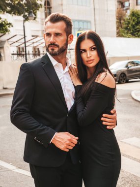 Güzel moda kadını ve takım elbiseli yakışıklı erkek arkadaşı. Siyah gece elbisesi içinde seksi esmer manken. Avrupa 'da sokakta poz veren şık bir çift. Vahşi adam ve dişisi açık havada