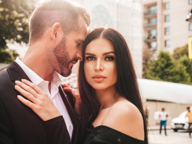 Güzel moda kadını ve takım elbiseli yakışıklı erkek arkadaşı. Siyah gece elbisesi içinde seksi esmer manken. Avrupa 'da sokakta poz veren şık bir çift. Vahşi adam ve dişisi açık havada