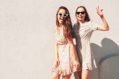 Son moda yaz kıyafetleri içinde iki güzel gülümseyen hippi kadın. Sokakta poz veren kaygısız kadınlar. Pozitif saf modeller gün batımında eğleniyor, sarılıyor ve deliriyor. Mutlu ve neşeli.