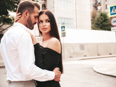 Güzel moda kadını ve takım elbiseli yakışıklı erkek arkadaşı. Siyah gece elbisesi içinde seksi esmer manken. Avrupa 'da sokakta poz veren şık bir çift. Vahşi adam ve dişisi açık havada