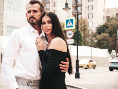 Güzel moda kadını ve takım elbiseli yakışıklı erkek arkadaşı. Siyah gece elbisesi içinde seksi esmer manken. Avrupa 'da sokakta poz veren şık bir çift. Vahşi adam ve dişisi açık havada