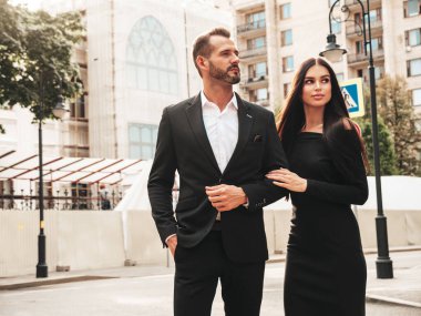 Güzel moda kadını ve takım elbiseli yakışıklı erkek arkadaşı. Siyah gece elbisesi içinde seksi esmer manken. Avrupa 'da sokakta poz veren şık bir çift. Vahşi adam ve dişisi açık havada