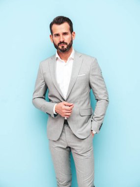 Yakışıklı, kendine güvenen, stil sahibi, Lambersex modelinin portresi. Zarif takım elbise giymiş modern bir adam. Moda erkeği stüdyoda mavi duvarın yanında poz veriyor. Kameraya bakıyorum.