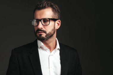 Yakışıklı, kendine güvenen, havalı hipster Lambersex modelinin yakın plan portresi. Zarif siyah takım elbiseli seksi modern adam. Moda erkeği karanlık arka planda stüdyoda poz veriyor. Gözlüklerle