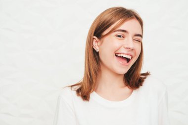 Yeni moda hippi kıyafetleri içinde gülümseyen güzel bir kadının yakın plan portresi. Stüdyoda gri arka planda poz veren kaygısız seksi kadın. Pozitif model içeride eğleniyor. Göz kırpma