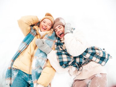 Son moda sıcak kıyafetler ve eşarplar içinde iki güzel, gülümseyen hippi kadın. Parktaki sokakta poz veren tasasız kadınlar. Karda yatan pozitif saf modeller. Kış anlarının tadını çıkarıyorum. Xmas kavramı