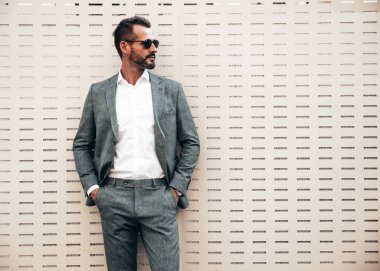 Yakışıklı, kendine güvenen, stil sahibi, Lambersex modelinin portresi. Zarif takım elbise giymiş modern bir adam. Moda erkeği gün batımında Avrupa şehrinin arka planında poz veriyor. Güneş gözlükleriyle