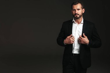 Yakışıklı, kendine güvenen, stil sahibi hipster Lambersex modelinin portresi. Zarif siyah takım elbiseli seksi modern adam. Moda erkeği karanlık arka planda stüdyoda poz veriyor. Kameraya bakıyorum. 