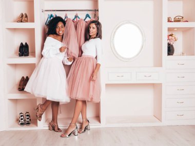 Son moda yaz elbiseleri içinde gülümseyen iki güzel uluslararası hippi kadın. Pembe gardıropta poz veren kaygısız seksi kadınlar. Pozitif modeller eğleniyor. Arkadaşlık kavramı. Tutma elbisesi