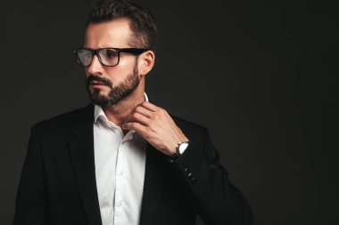 Yakışıklı, kendine güvenen, havalı hipster Lambersex modelinin yakın plan portresi. Zarif siyah takım elbiseli seksi modern adam. Moda erkeği karanlık arka planda stüdyoda poz veriyor. Gözlüklerle