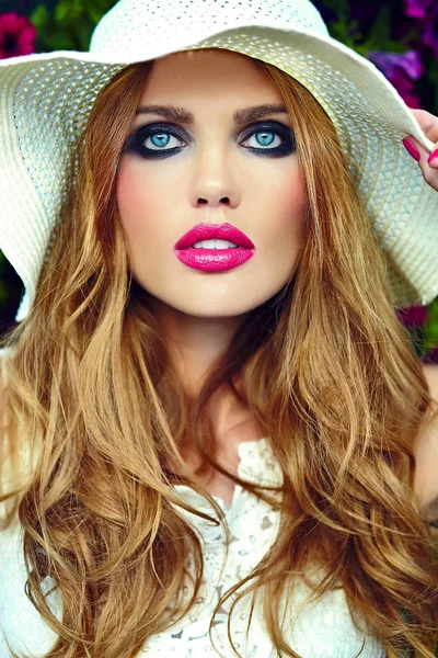 High fashion look.glamor closeup portrait of beautiful sexy stylish blond young woman model with bright makeup and pink lips with perfect clean skin in hat near summer flowers — Stock Photo, Image