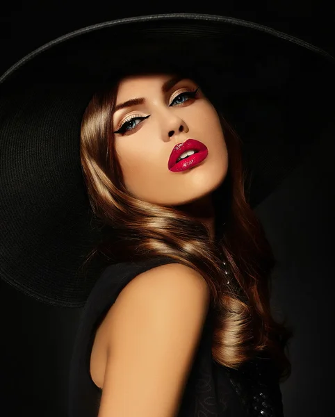 High fashion look.glamor closeup portrait of beautiful sexy stylish  Caucasian young woman model with bright makeup, with red lips,  with perfect clean skin in big black hat Royalty Free Stock Images