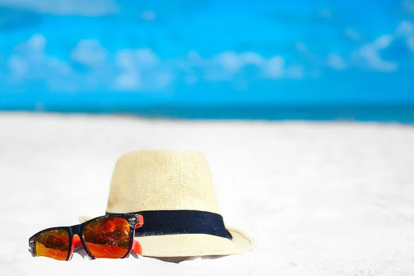 帽子和多彩太阳镜上夏天白色沙滩附近蓝色的海洋 — 图库照片