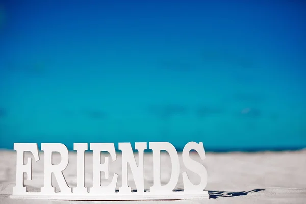 Name friends on white sand behind blue sky near ocean — Stock Photo, Image