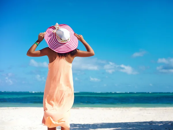 炎热的夏日，穿着艳丽的太阳帽，穿着华丽的衣服，走在海滨的海面上，站在白沙滩上 — 图库照片