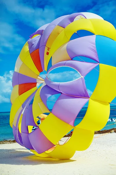 Arco-íris colorido brilhante Paraquedas na praia atrás da água azul do oceano — Fotografia de Stock