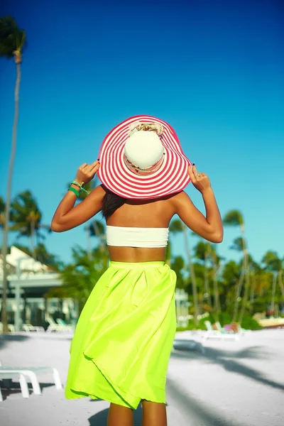 High fashion look. back of glamor sexy model girl  in retro style with palms  in colorful cloth and sunhat behind blue beach  sky — Stock Photo, Image