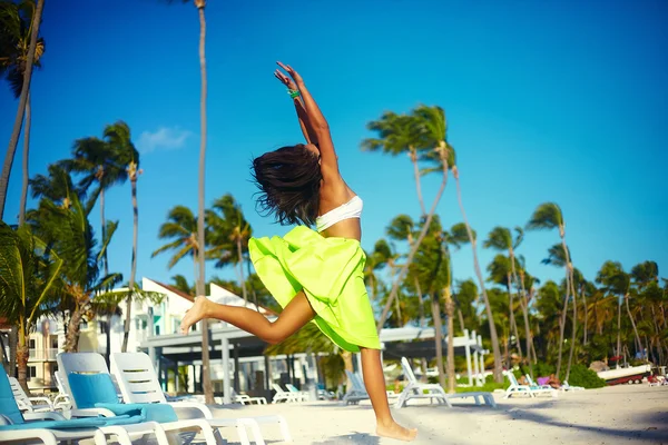 Ευτυχισμένος αστικών σύγχρονο κομψό κοπέλα κορίτσι μοντέλο σε φωτεινά σύγχρονες πανί στο πράσινο πολύχρωμη φούστα σε εξωτερικούς χώρους στην παραλία το καλοκαίρι άλμα πίσω από το γαλάζιο του ουρανού — Φωτογραφία Αρχείου