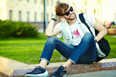 Komik gülümseyen hipster yakışıklı çocuk güneş gözlüğü sokakta şık kumaş