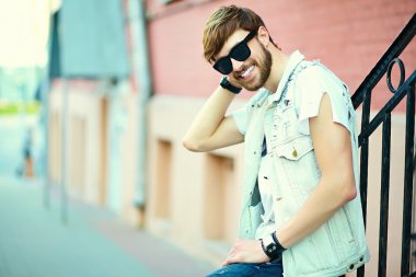 Komik gülümseyen hipster yakışıklı çocuk güneş gözlüğü sokakta şık kumaş