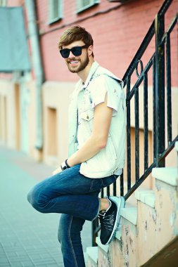 Komik gülümseyen hipster yakışıklı çocuk güneş gözlüğü sokakta şık kumaş