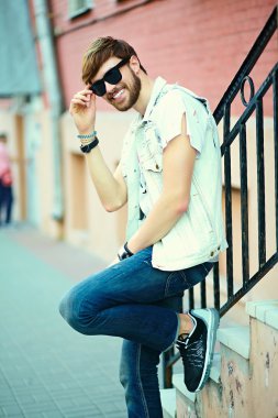 Komik gülümseyen hipster yakışıklı çocuk güneş gözlüğü sokakta şık kumaş
