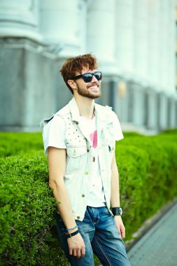 Komik gülümseyen hipster yakışıklı çocuk güneş gözlüğü sokakta şık kumaş