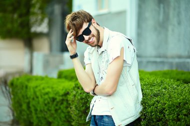 Komik gülümseyen hipster yakışıklı çocuk güneş gözlüğü sokakta şık kumaş