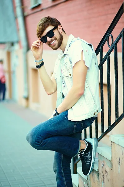 Engraçado sorrindo hipster homem bonito cara em pano elegante na rua em óculos de sol — Fotografia de Stock