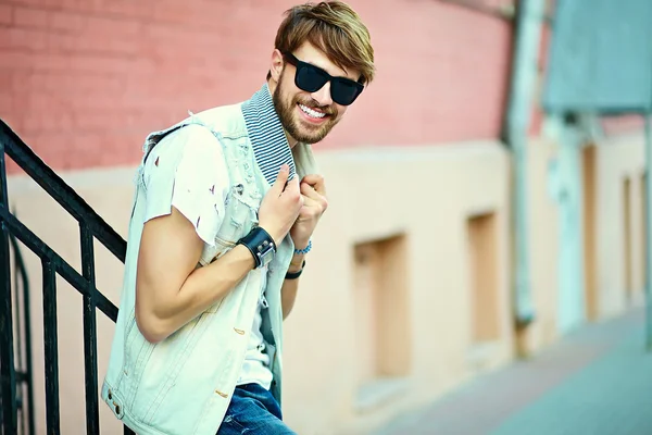 Divertente sorriso hipster bel ragazzo uomo in stoffa elegante in strada in occhiali da sole — Foto Stock
