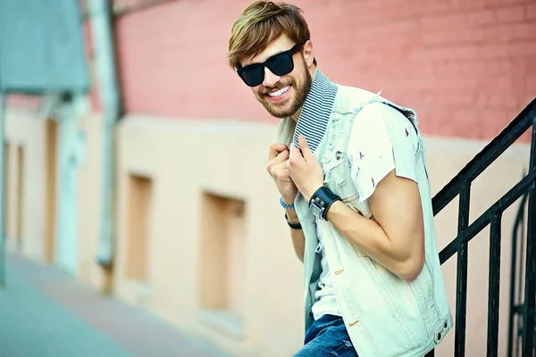 Funny smiling hipster handsome man guy in stylish cloth in the street in sunglasses