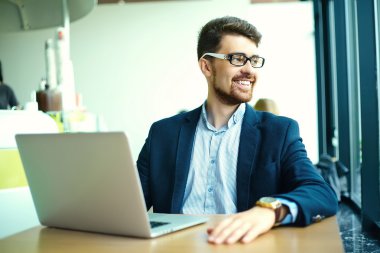 Young fashion smiling hipster man drinking  coffee in the city cafe during lunch time with notebook in suit