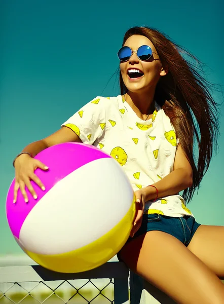 Funny crazy glamor stylish sexy smiling beautiful young woman model in  bright hipster summer casual cloth with colorful ball in the street behind blue sky — Stock Photo, Image