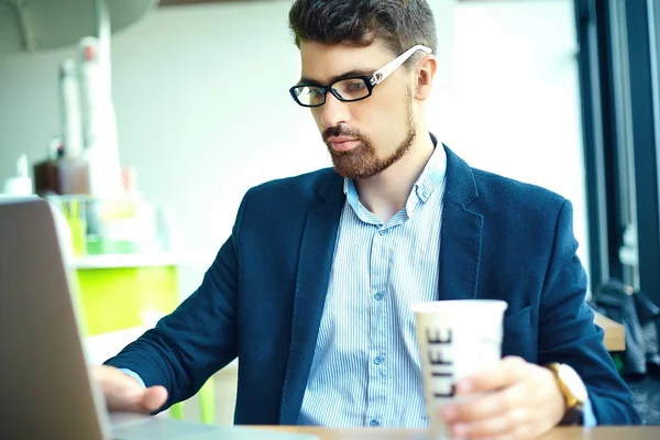 Junger Mode lächelnder Hipster-Mann beim Kaffeetrinken im Stadtcafé zur Mittagszeit mit Notebook im Anzug — Stockfoto