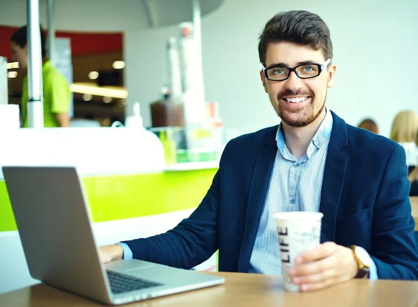 Junger Mode lächelnder Hipster-Mann beim Kaffeetrinken im Stadtcafé zur Mittagszeit mit Notebook im Anzug — Stockfoto