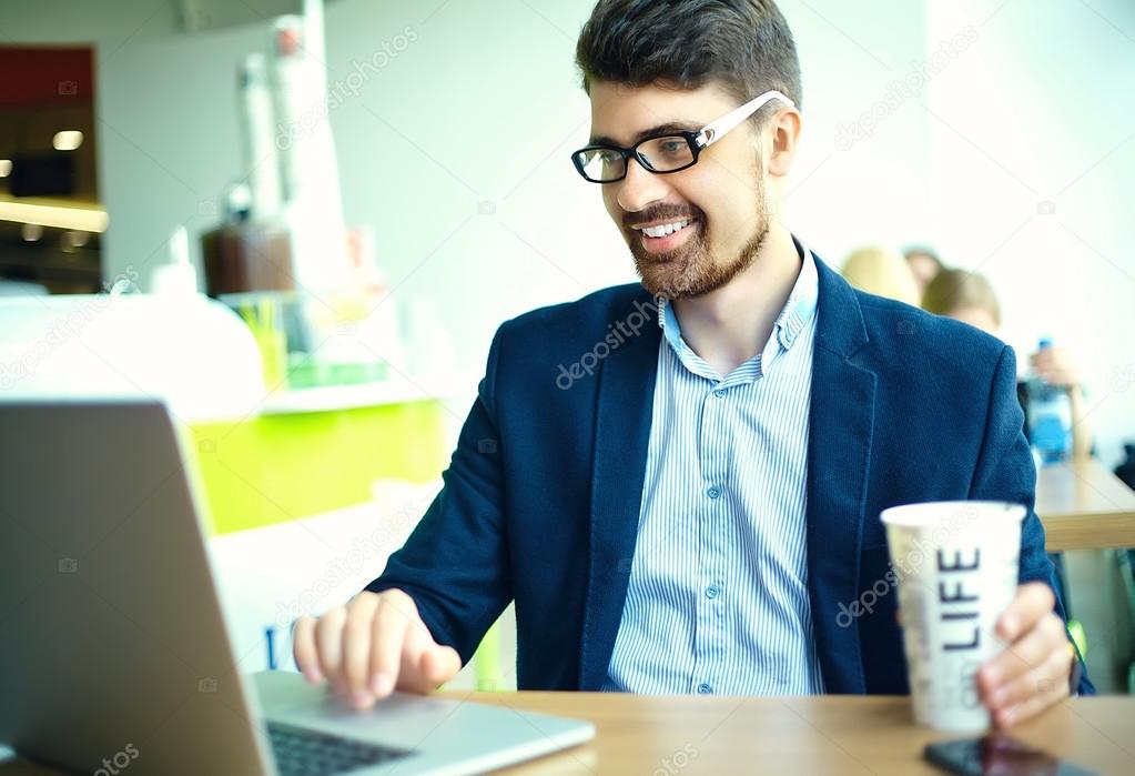 Young fashion smiling hipster man drinking  coffee in the city cafe during lunch time with notebook in suit