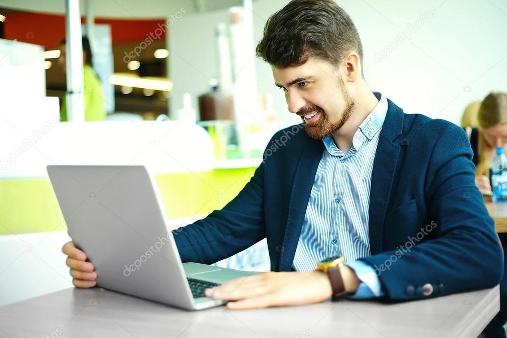 Young fashion smiling hipster man drinking  coffee in the city cafe during lunch time with notebook in suit