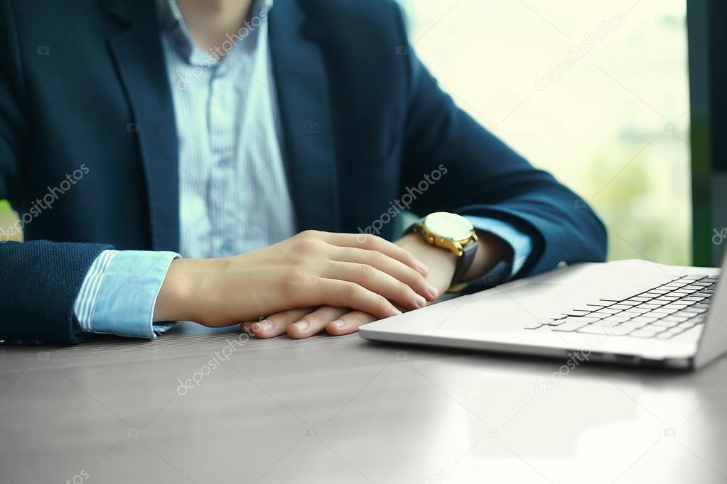 Young man working with laptop, man's hands on notebook computer, business person at workplace