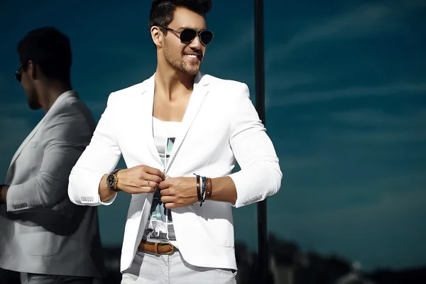 Retrato de moda de hombre de negocios sexy joven modelo guapo en traje de tela casual en gafas de sol en la calle detrás del cielo azul — Foto de Stock
