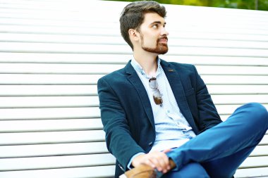Young handsome hipster Male Student Sitting on the Bench in a Park in suit