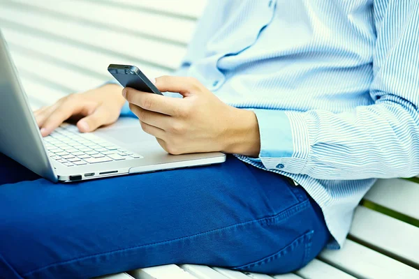 Young man working with laptop, man's hands on notebook computer, business person in casual clothes in the street — Stock Photo, Image