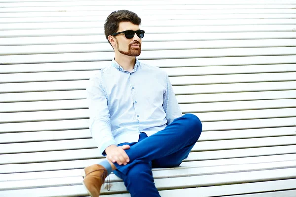 Joven guapo hipster Hombre Estudiante sentado en el banco en un parque — Foto de Stock