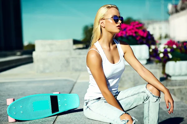 High fashion look.glamor stylish sexy beautiful young blond  model girl in summer bright casual hipster clothes with skateboard sitting in the street — Φωτογραφία Αρχείου