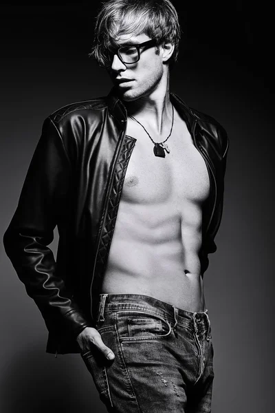 Genç, kaslı, formda bir erkek model stüdyoda karın kaslarını gösteriyor.