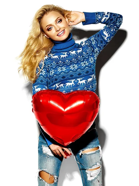 Retrato de hermosa chica rubia sonriente dulce feliz sosteniendo en sus manos gran globo de corazón rojo en ropa de invierno caliente hipster casual, en suéter azul —  Fotos de Stock