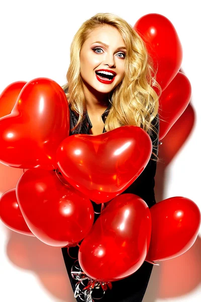 Portrait of beautiful happy sweet smiling blonde woman girl holding in her hands red heart balloons in casual black hipster clothes — Stock Photo, Image