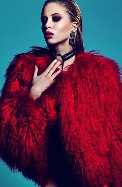 fashion glamor stylish swag young woman model in hipster red fur coat with bright makeup on blue background