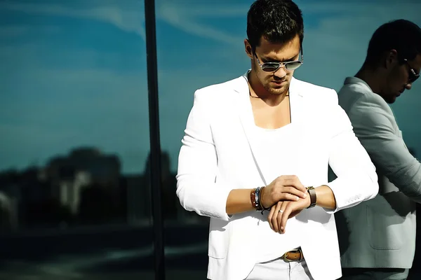 Fashion portrait of young sexy handsome model man in casual white suit in sunglasses in white suit in the street — Φωτογραφία Αρχείου