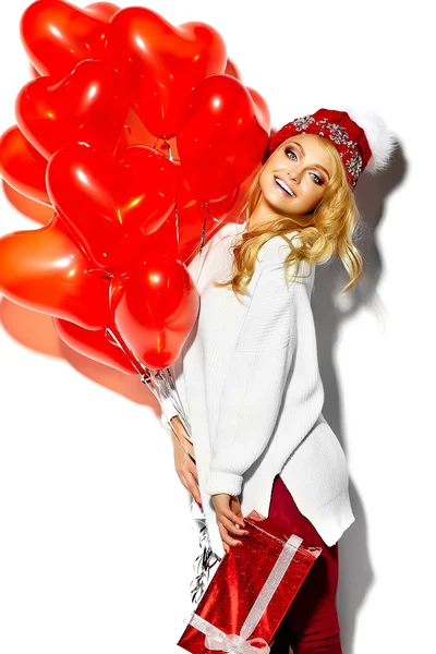 美丽快乐甜蜜微笑金发女人的女孩她手里拿着大圣诞礼物盒和心气球在休闲红色时髦冬天的衣服，在温暖的白毛衣的肖像 — 图库照片